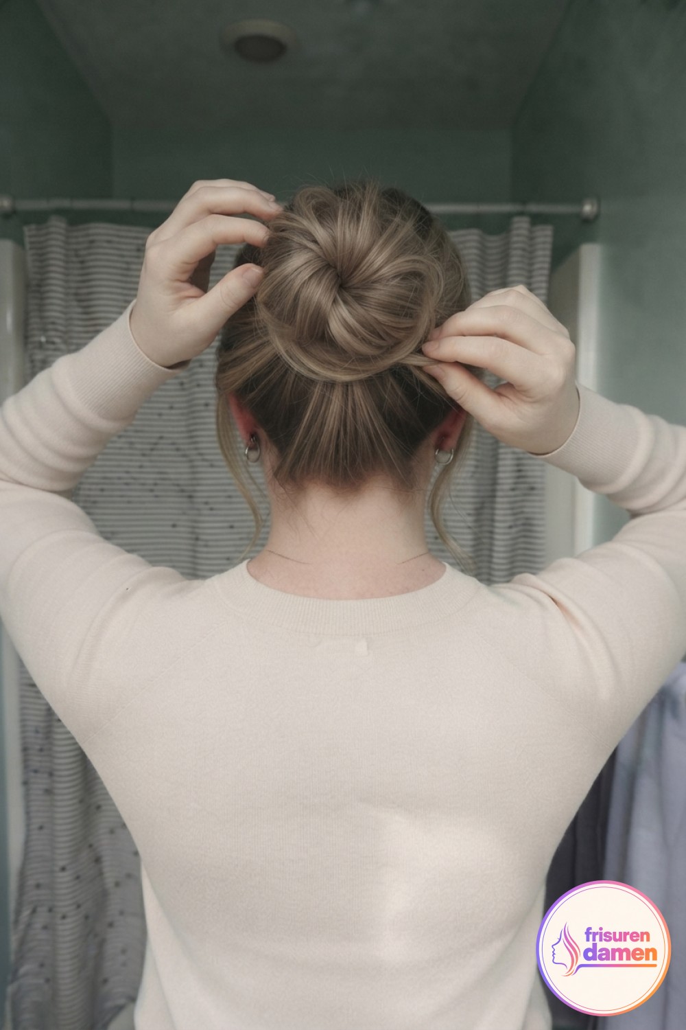Nahaufnahme zeigt, wie lose Enden in den Ansatz des lockeren Messy Bun getuckt und die Krone aufgelockert wird.