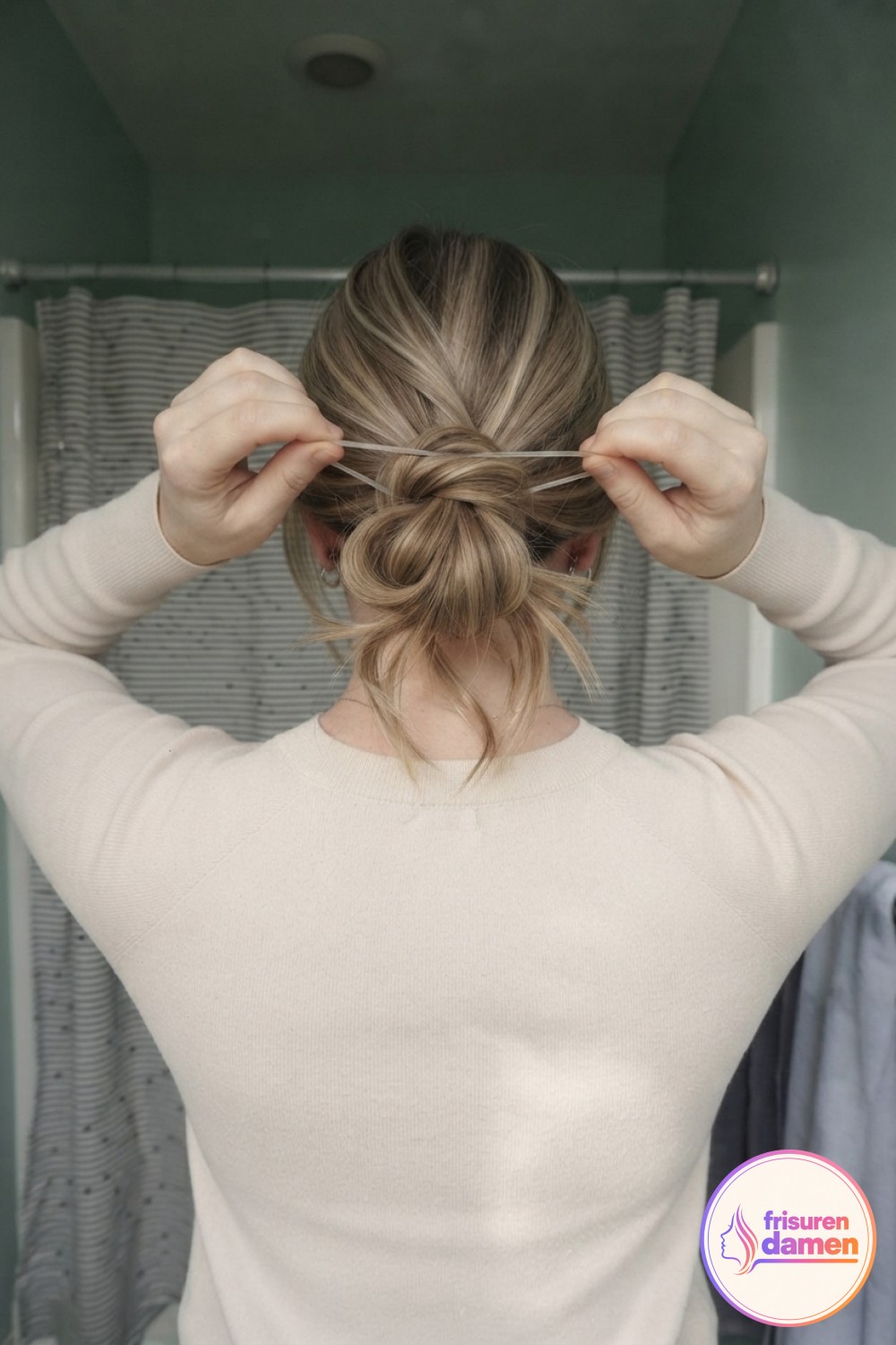 Ein dünnes Haargummi wird um den losen Dutt gewickelt, ein wichtiger Kniff im lockeren Messy Bun Tutorial.