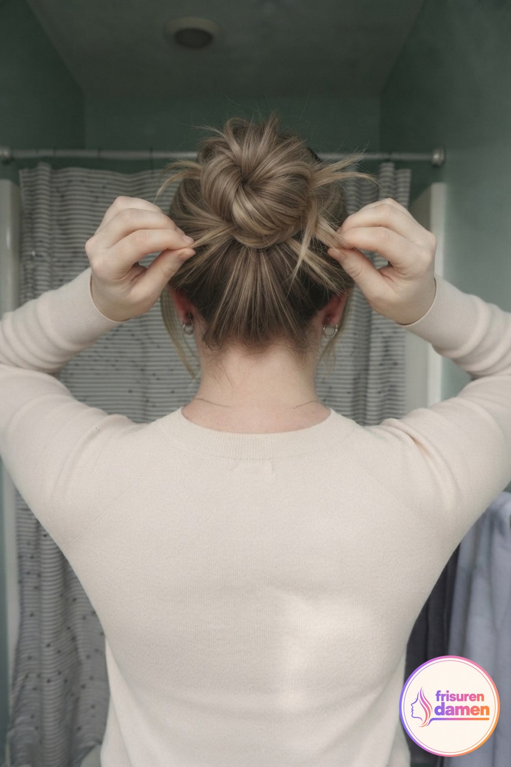 Finger ziehen einzelne Strähnen aus dem Dutt, damit der lockere Messy Bun mehr Volumen bekommt.